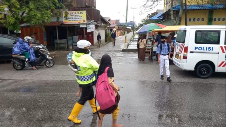  Ditengah Guyuran Hujan, Kasat Lantas Polres Dumai Dorong Motor dan Seberangkan Pelajar