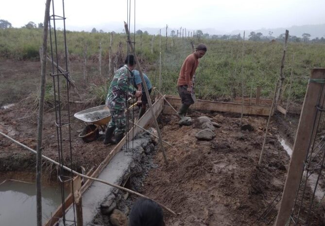  Babinsa Koramil 1311-08/Soyo Jaya Bantu Pembangunan Fondasi Rumah Warga Binaan di Desa Bau